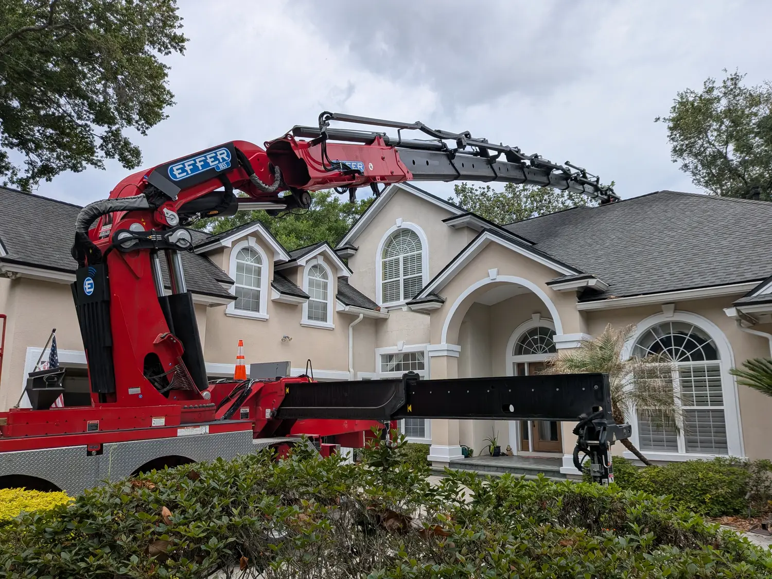 Knuckle-boom crane working carefully over an established Jacksonville home