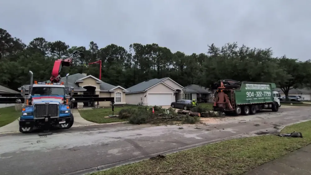 Jax Tree Removal crane truck clearing a storm-fallen tree from an Arlington street with cut sections staged, Jacksonville FL