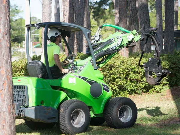 Compact articulated loader clearing brush — tree service in Jacksonville, FL by Jax Tree Removal
