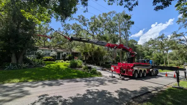 Jax Tree Removal red Effer knuckle-boom crane on a blue Western Star truck extending its boom into a live oak while an aerial lift works up in the canopy, Jacksonville, FL