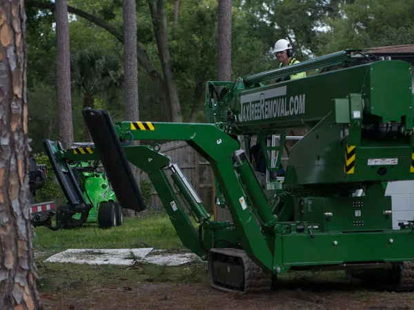 Green JaxTreeRemoval.com spider crane on site — tree service in Jacksonville, FL by Jax Tree Removal