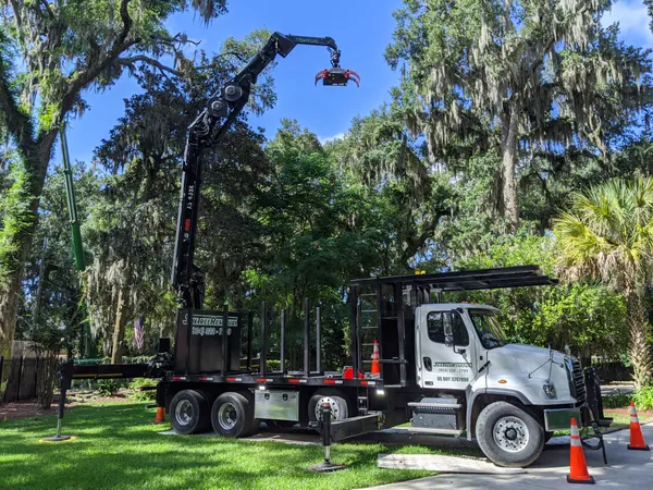 Branded knuckle-boom crane truck with grapple under a live oak — crane tree removal in Jacksonville, FL by Jax Tree Removal