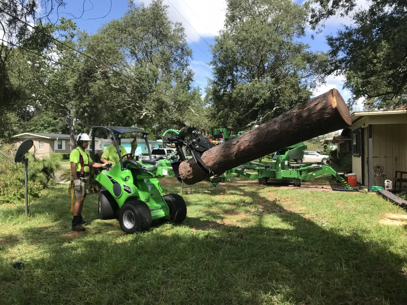 Green articulated loader carrying a log with the grapple — tree removal in Jacksonville, FL by Jax Tree Removal