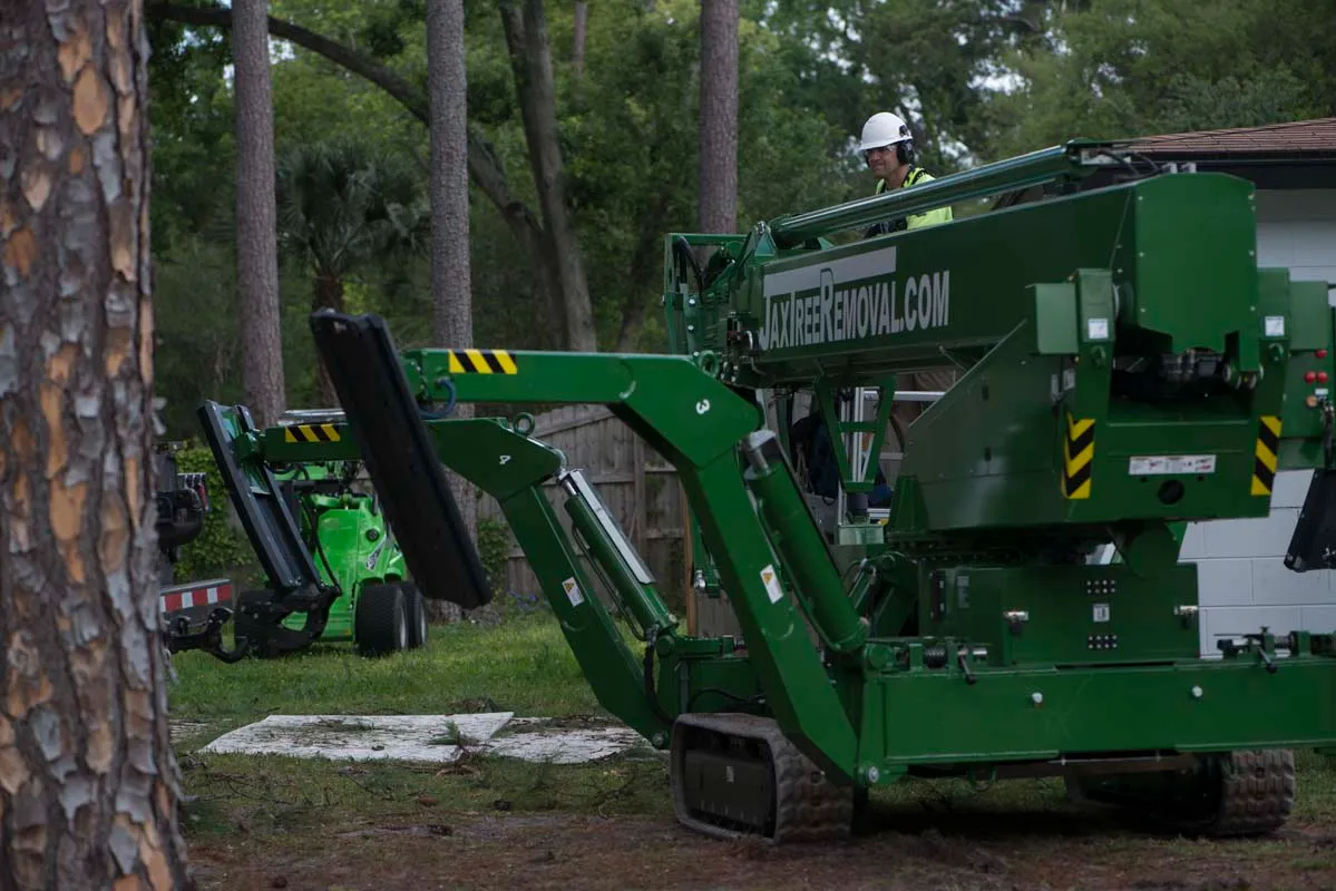 Green JaxTreeRemoval.com spider crane on site — tree service in Jacksonville, FL by Jax Tree Removal