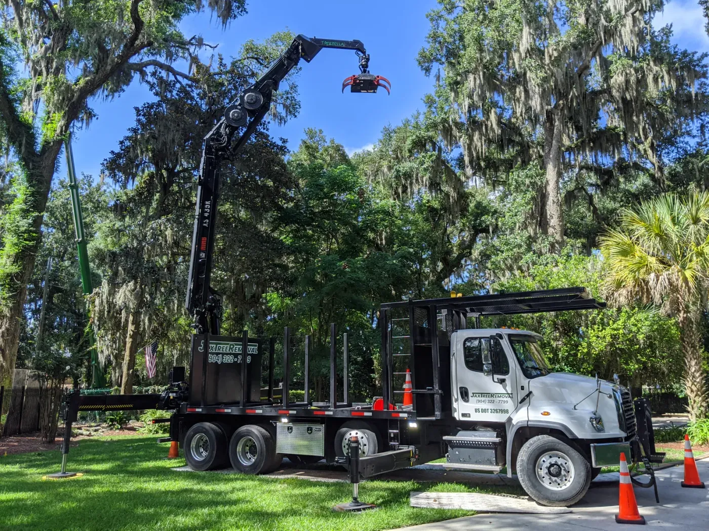 Branded knuckle-boom crane truck with grapple under a live oak — crane tree removal in Jacksonville, FL by Jax Tree Removal